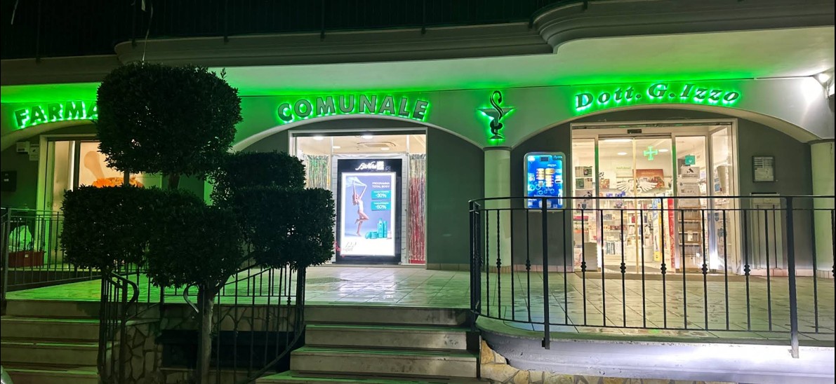 Illustrazione della facciata della Farmacia Comunale di Portico di Caserta, con insegna verde e croce di farmacia.